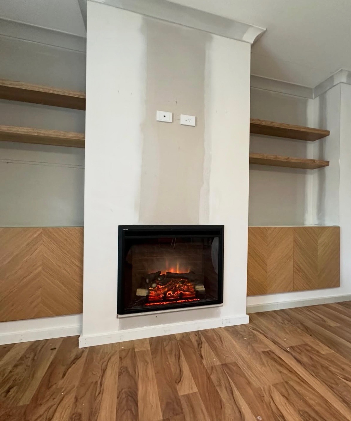 Custom fireplace surround with herringbone timber panelling and floating shelves